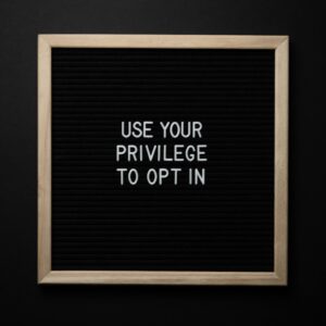 From above composition of contrast blackboard in wooden frame with white USE YOUR PRIVILEGE TO OPT IN title on black background